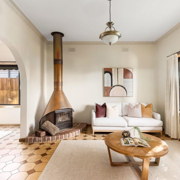 Vintage living room styling in Melbourne with warm neutral tones, structured cushions, and a feature fireplace with arched entry
