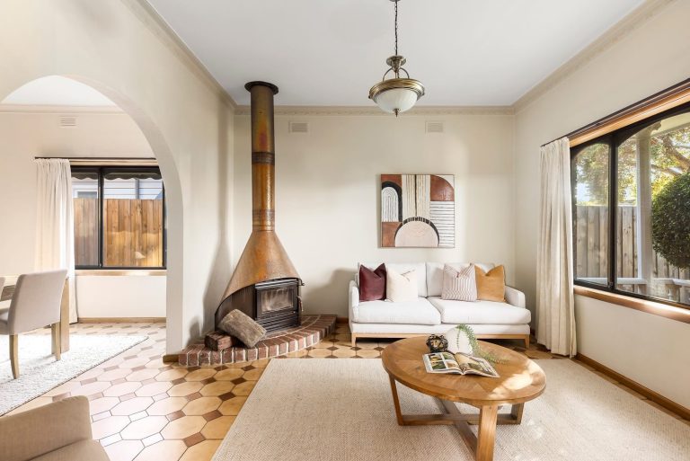 Vintage living room styling in Melbourne with warm neutral tones, structured cushions, and a feature fireplace with arched entry