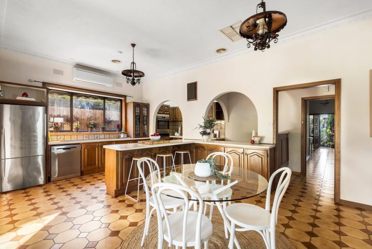 Open-plan vintage kitchen and dining area with timber cabinetry, terracotta flooring, and light modern styling in Melbourne home
