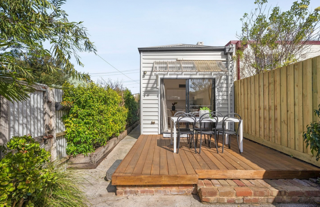 Sunny rear timber deck with outdoor dining setting and established garden in a house in Brunswick.