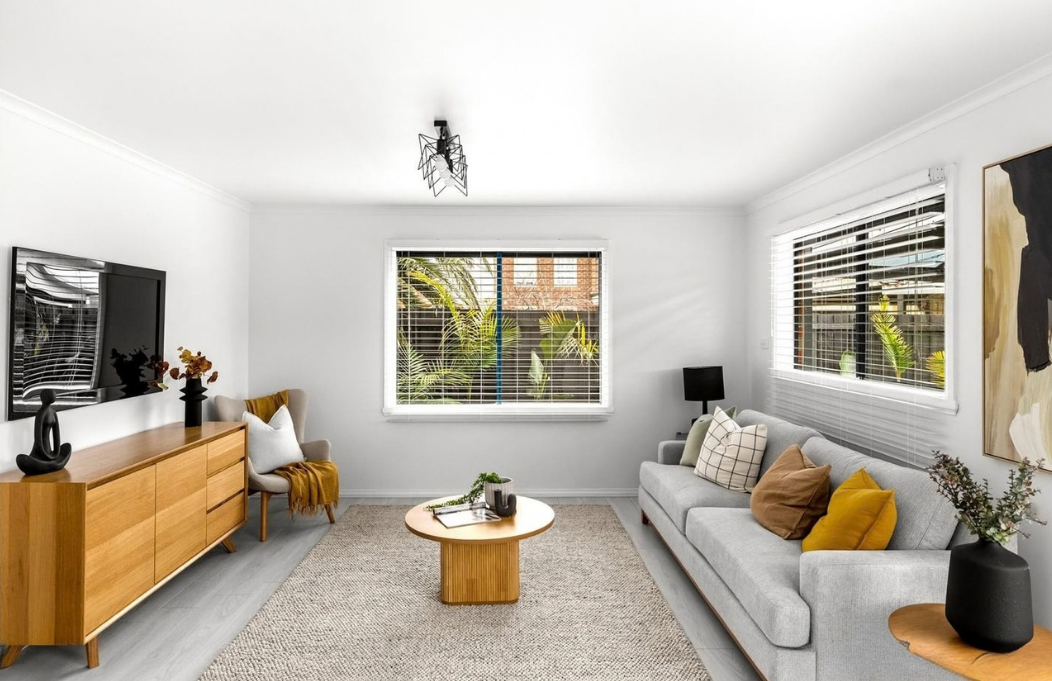 Light-filled living room styled with a grey sofa, warm timber furniture and mustard accents.