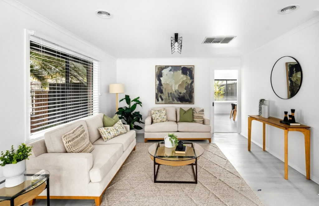 Neutral living room styled with cream sofas, warm timber furniture, black accents and abstract artwork.